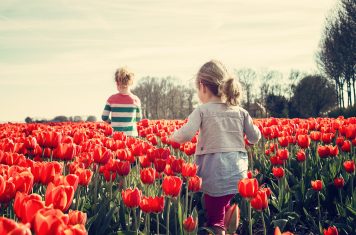 twee kinderen kind in een veld vol bloemen meisje tulpen rood