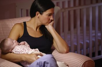 Vrouw met kind baby kijkt verdrietig depressief nadenkend bruin zwart haar baby slaapt