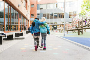 Girls (8-9) embracing and walking together